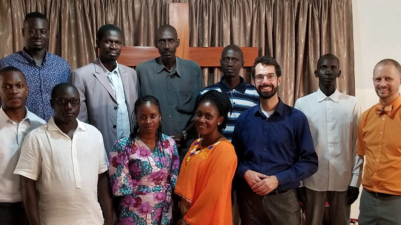 Zendeling staat in groep met Senegalezen geposeerd